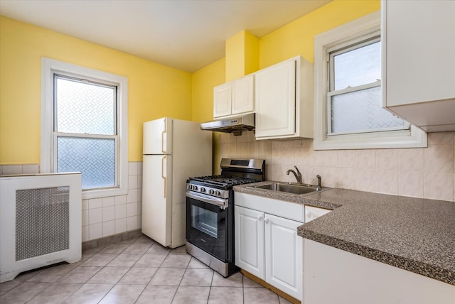 51-17 47th St Unit 2, Woodside, NY 11377 - kitchen with stainless steel gas stove, under cabinet range hood, tile walls, dark countertops, and white cabinets