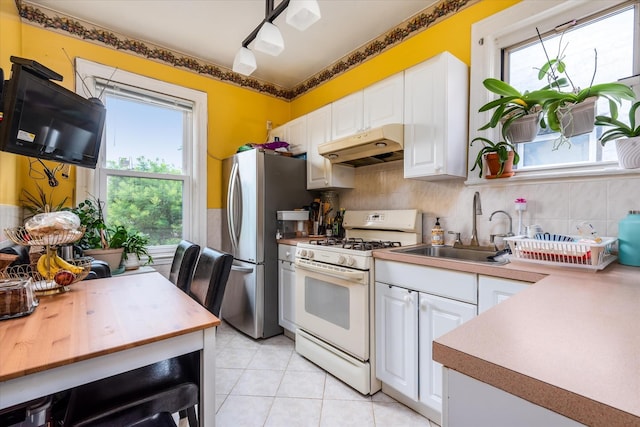 51-17 47th St Unit 2, Woodside, NY 11377 - kitchen featuring white range with gas stovetop, under cabinet range hood, freestanding refrigerator, white cabinetry, and decorative backsplash