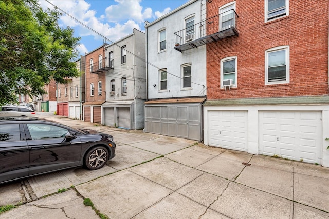 51-17 47th St Unit 2, Woodside, NY 11377 - view of side of home featuring a garage, brick siding, concrete driveway, a residential view, and stucco siding