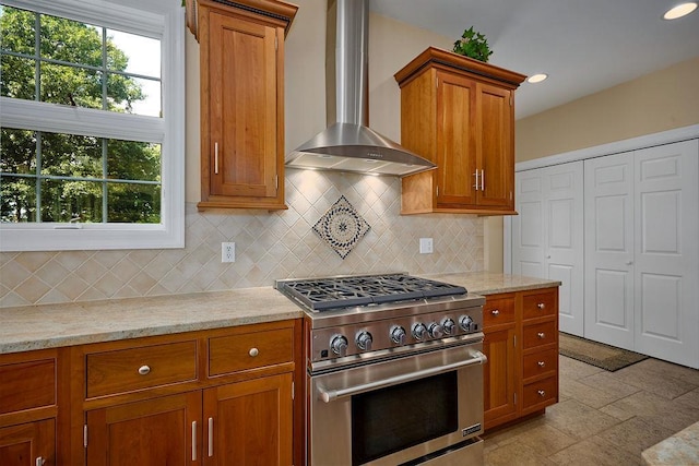 90 River Rd, Hyde Park, NY 12538 - kitchen featuring high end stove, wall chimney exhaust hood, brown cabinetry, backsplash, and light stone counters