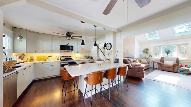 114 Shetland Dr, New City, NY 10956 - kitchen featuring stainless steel appliances, ceiling fan, dark wood-style flooring, a kitchen bar, and light stone countertops