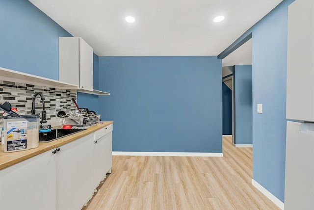 299 Orchid Dr, Mastic Beach, NY 11951 - kitchen with tasteful backsplash, white cabinetry, light wood-style flooring, recessed lighting, and black electric stovetop