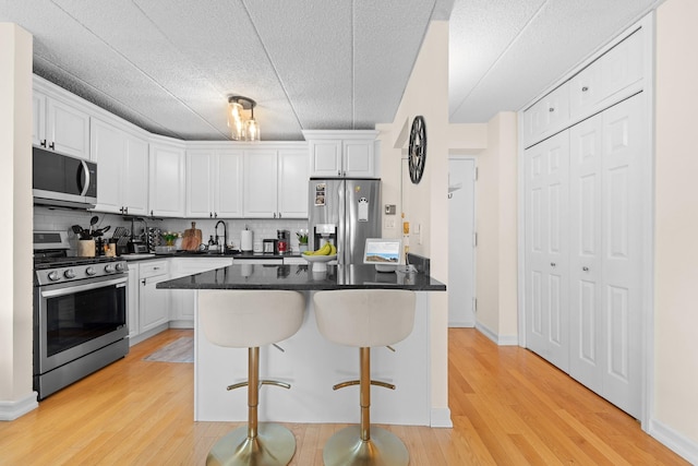 3220 Fairfield Ave Unit 6A, Bronx, NY 10463 - kitchen with appliances with stainless steel finishes, white cabinets, tasteful backsplash, dark countertops, and light wood finished floors