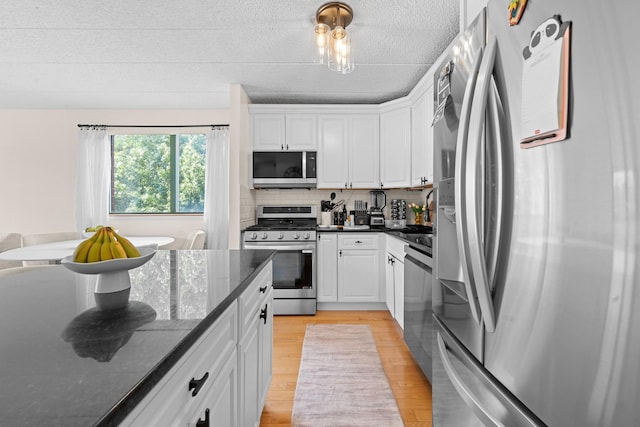 3220 Fairfield Ave Unit 6A, Bronx, NY 10463 - kitchen with appliances with stainless steel finishes, white cabinets, tasteful backsplash, a textured ceiling, and light wood-style flooring