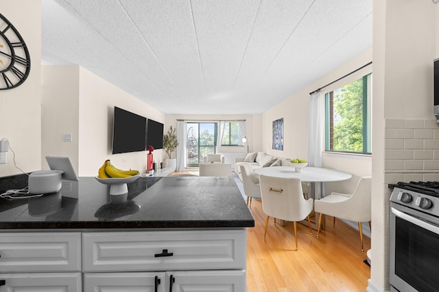 3220 Fairfield Ave Unit 6A, Bronx, NY 10463 - kitchen featuring gas range, light wood finished floors, open floor plan, dark stone countertops, and white cabinetry