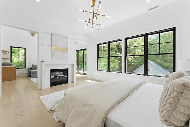 7 Rosemary Ln, Sag Harbor, NY 11963 - bedroom with a chandelier, light wood finished floors, and a glass covered fireplace
