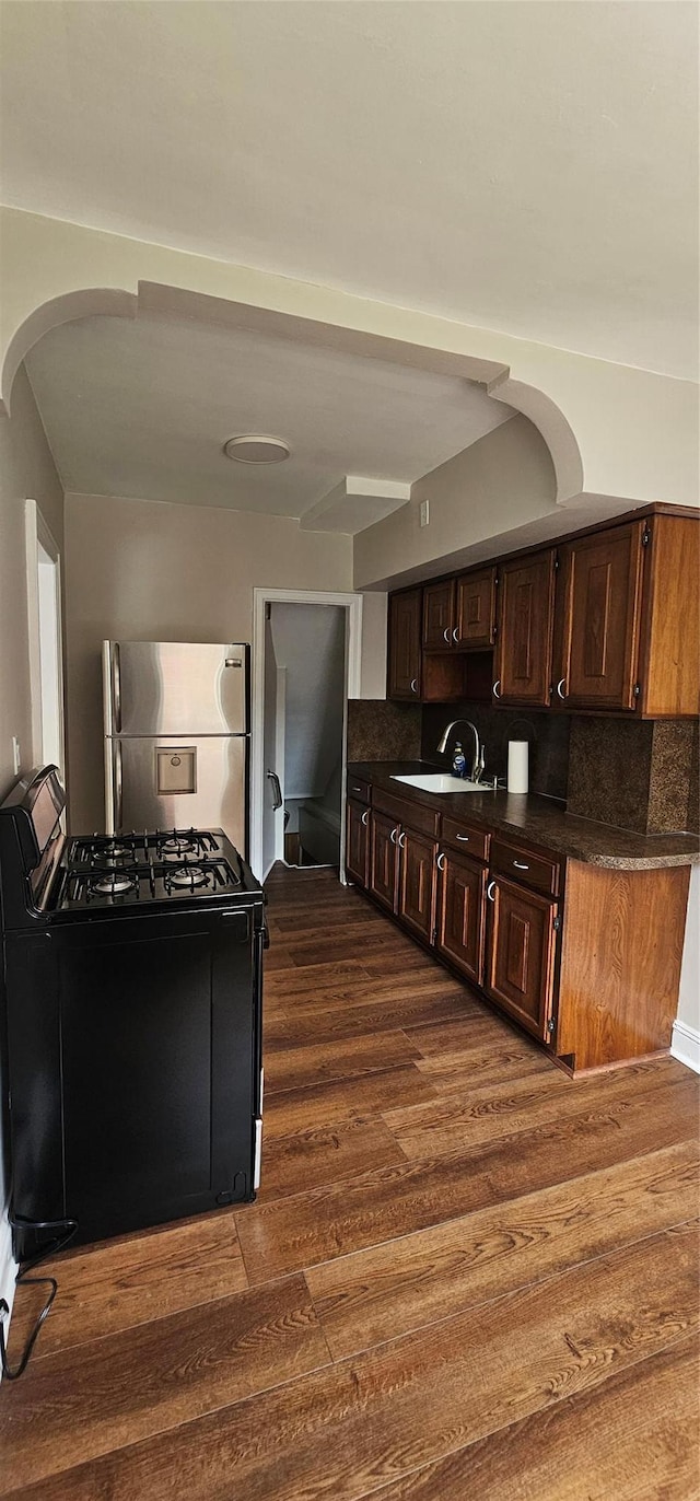 5203 72nd Pl, Maspeth, NY 11378 - kitchen with freestanding refrigerator, black range with gas stovetop, dark countertops, and arched walkways