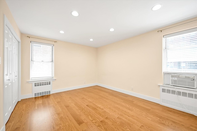 65-05 Yellowstone Blvd Unit 1A, Forest Hills, NY 11375 - unfurnished bedroom with radiator heating unit, multiple windows, light wood-style flooring, and recessed lighting