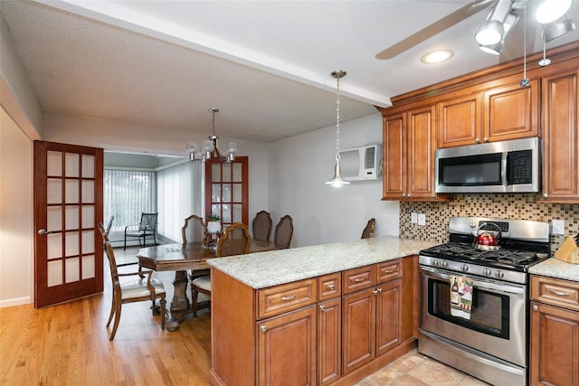 24 Hickory St, Deer Park, NY 11729 - kitchen featuring appliances with stainless steel finishes, a peninsula, brown cabinetry, and tasteful backsplash