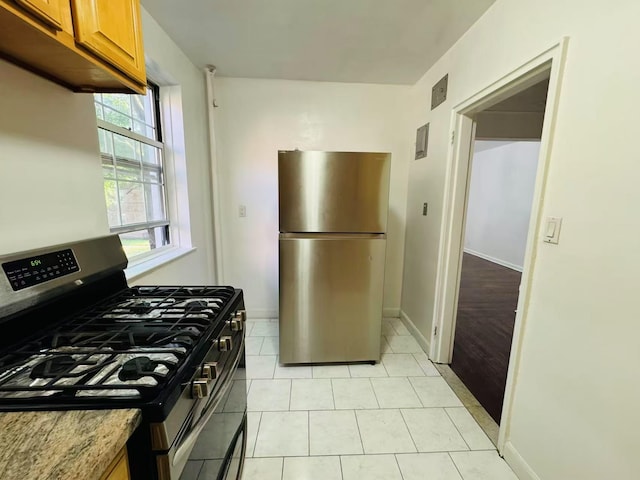 77-04 141st St Unit 67F, Flushing, NY 11367 - kitchen with stainless steel appliances, brown cabinets, light tile patterned flooring, and light stone countertops