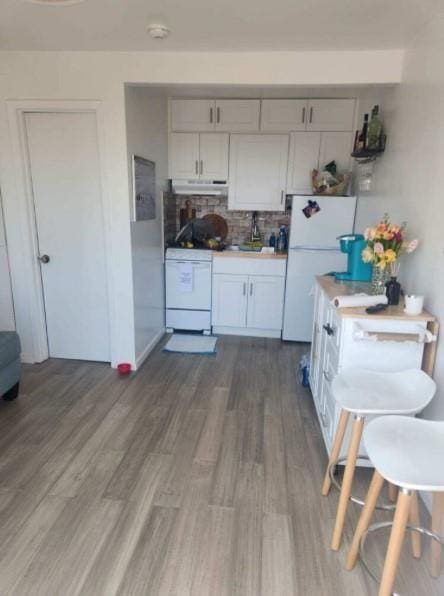 176 Ocean Walk Unit 17, Cherry Grove, NY 11782 - kitchen featuring white appliances, dark wood-style flooring, under cabinet range hood, and tasteful backsplash