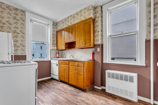 13-19 126th St, College Point, NY 11356 - kitchen featuring radiator heating unit, wallpapered walls, white appliances, light wood finished floors, and brown cabinetry