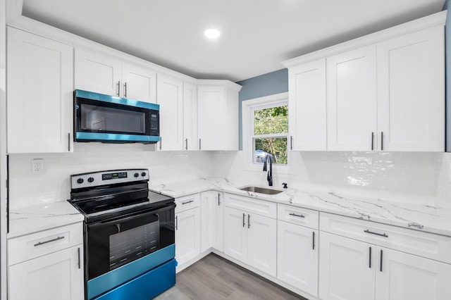 111A Wood Ave, Mastic, NY 11950 - kitchen with stainless steel microwave, electric range oven, white cabinetry, light wood-style flooring, and light stone countertops