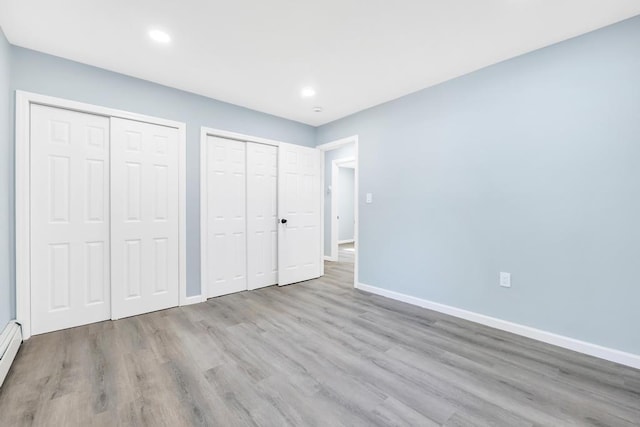 111A Wood Ave, Mastic, NY 11950 - unfurnished bedroom featuring multiple closets, wood finished floors, recessed lighting, and baseboard heating
