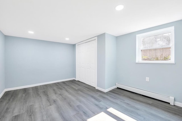 111A Wood Ave, Mastic, NY 11950 - unfurnished bedroom with a baseboard radiator, wood finished floors, a closet, and recessed lighting