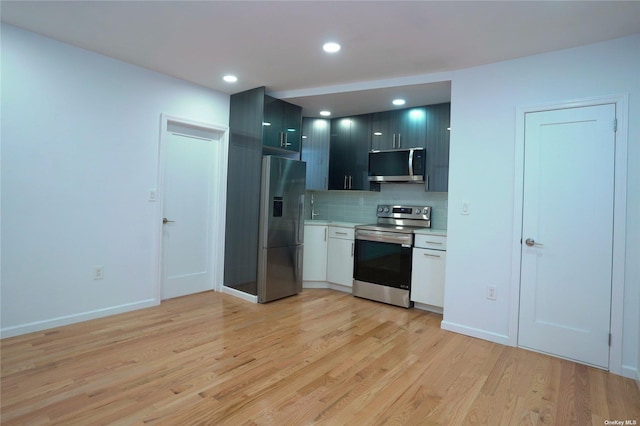 87-44 89th St, Woodhaven, NY 11421 - kitchen featuring stainless steel appliances, light countertops, light wood finished floors, tasteful backsplash, and recessed lighting
