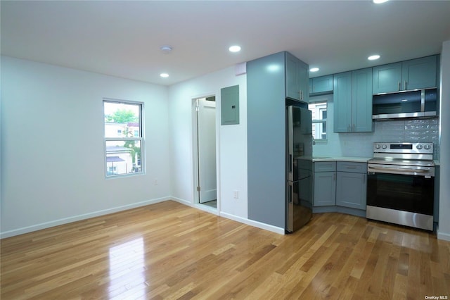 87-44 89th St, Woodhaven, NY 11421 - kitchen featuring appliances with stainless steel finishes, electric panel, light wood finished floors, light countertops, and backsplash