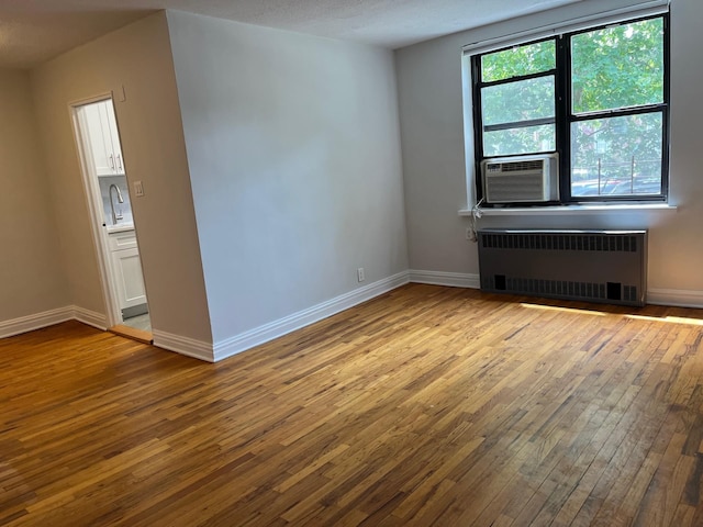 191-09 39th Ave Unit 164, Flushing, NY 11358 - spare room with radiator, wood-type flooring, and cooling unit