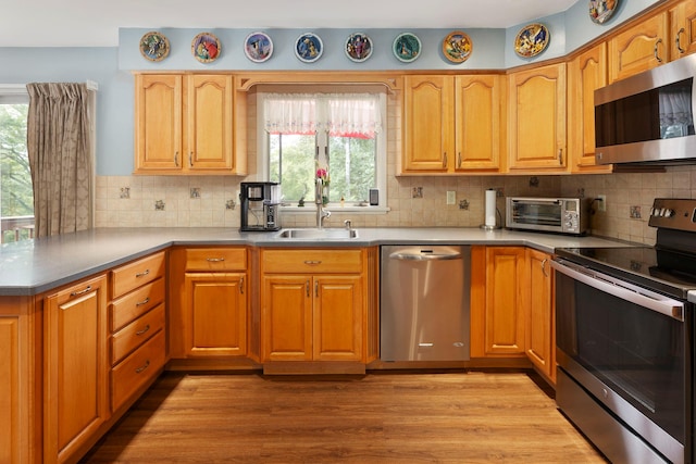 16 Mountain View Dr, Holmes, NY 12531 - kitchen featuring stainless steel appliances, a peninsula, backsplash, wood finished floors, and brown cabinetry