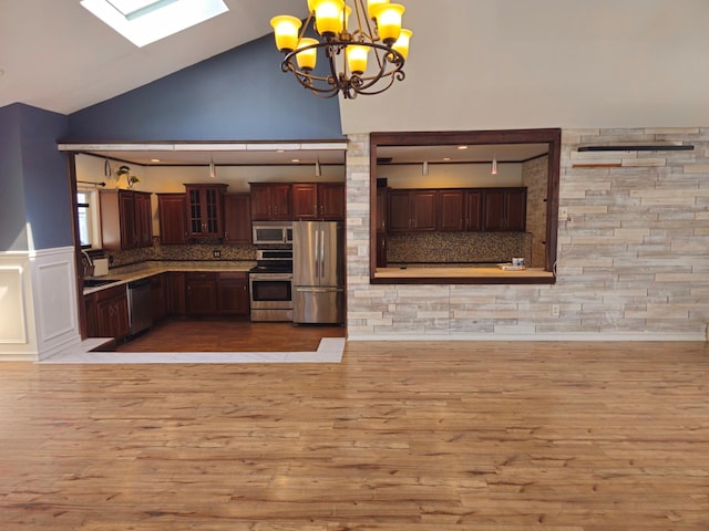 143 N Summit Ave, Patchogue, NY 11772 - kitchen with stainless steel appliances, light wood-style flooring, a skylight, a chandelier, and high vaulted ceiling
