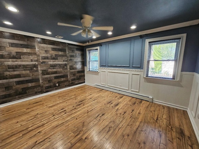 143 N Summit Ave, Patchogue, NY 11772 - unfurnished room featuring baseboard heating, a ceiling fan, wood-type flooring, wood walls, and ornamental molding