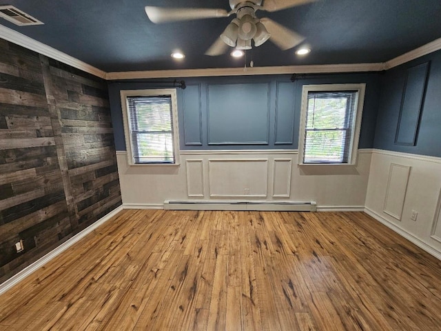 143 N Summit Ave, Patchogue, NY 11772 - empty room with a baseboard heating unit, ornamental molding, hardwood / wood-style floors, ceiling fan, and wooden walls