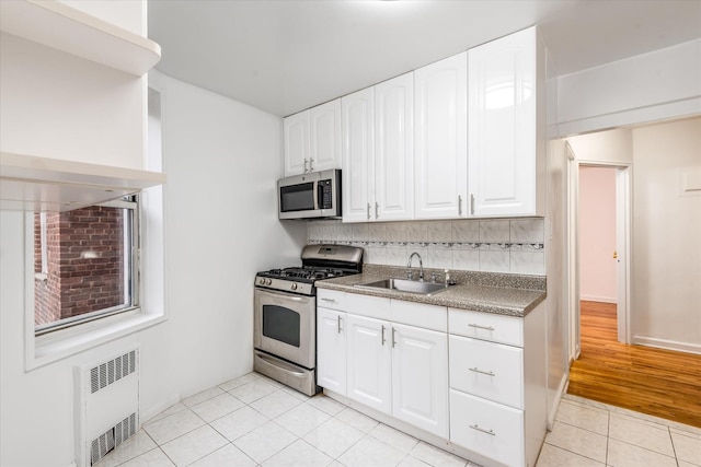67-30 Clyde St Unit 3L, Forest Hills, NY 11375 - kitchen with stainless steel appliances, radiator, light tile patterned flooring, and white cabinetry