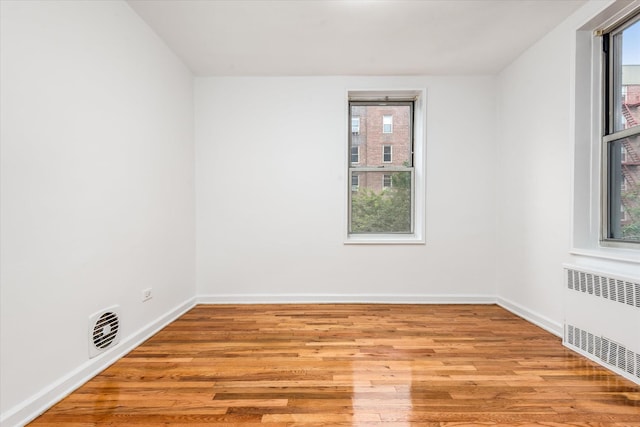 67-30 Clyde St Unit 3L, Forest Hills, NY 11375 - unfurnished room featuring radiator heating unit, wood finished floors, and healthy amount of natural light