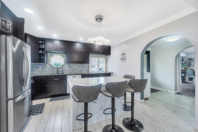 45 Potter Ln, Levittown, NY 11756 - kitchen featuring appliances with stainless steel finishes, a breakfast bar area, arched walkways, light wood finished floors, and a kitchen island