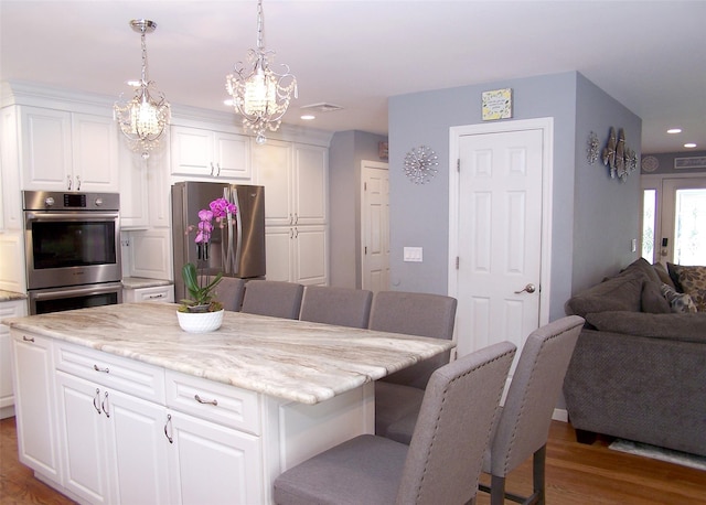 8 Mannes St, Ronkonkoma, NY 11779 - kitchen with appliances with stainless steel finishes, wood finished floors, a chandelier, open floor plan, and a breakfast bar area