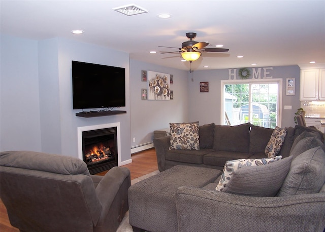 8 Mannes St, Ronkonkoma, NY 11779 - living room with a baseboard radiator, light wood finished floors, ceiling fan, recessed lighting, and a warm lit fireplace
