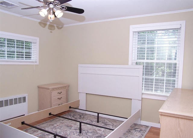 8 Mannes St, Ronkonkoma, NY 11779 - unfurnished bedroom with radiator, multiple windows, ornamental molding, wood finished floors, and ceiling fan