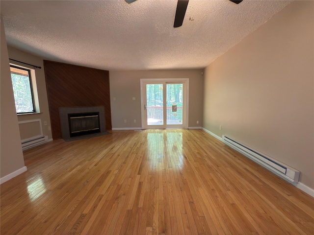 59 Meadowlark Ln, Woodridge, NY 12789 - unfurnished living room with a baseboard radiator, a textured ceiling, a fireplace with flush hearth, and healthy amount of natural light