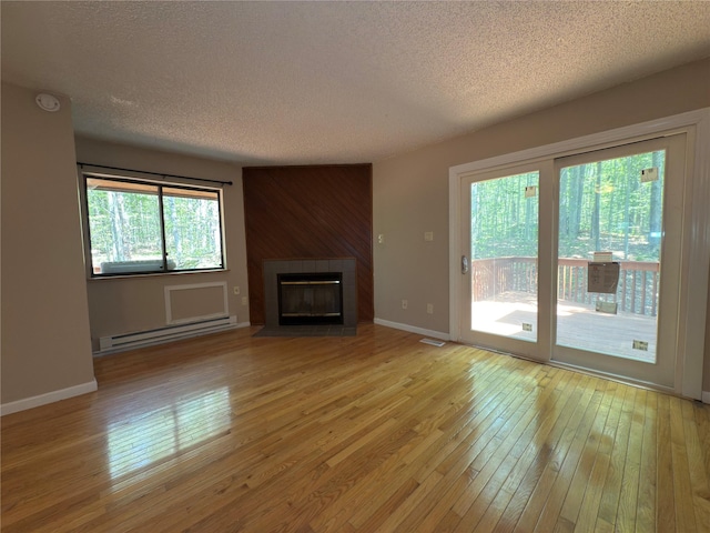 59 Meadowlark Ln, Woodridge, NY 12789 - unfurnished living room with a baseboard radiator, a textured ceiling, light wood-type flooring, and a tiled fireplace
