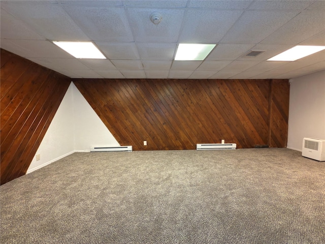 59 Meadowlark Ln, Woodridge, NY 12789 - below grade area with a baseboard heating unit, wood walls, carpet floors, and a paneled ceiling