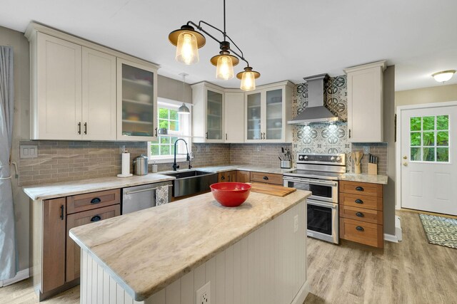 27 Balsam Rd, Hyde Park, NY 12538 - kitchen featuring wall chimney range hood, stainless steel appliances, light wood finished floors, a kitchen island, and hanging light fixtures