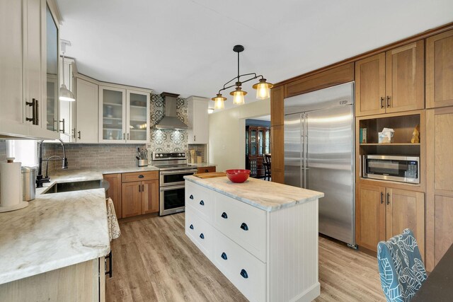 27 Balsam Rd, Hyde Park, NY 12538 - kitchen with appliances with stainless steel finishes, wall chimney range hood, light wood-style flooring, decorative backsplash, and a center island