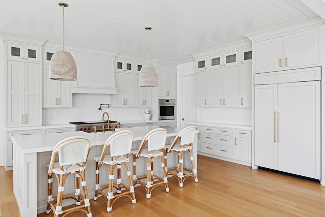 1 Fiske Ave, Westhampton Beach, NY 11978 - kitchen featuring paneled refrigerator, oven, light wood-style flooring, light countertops, and an island with sink