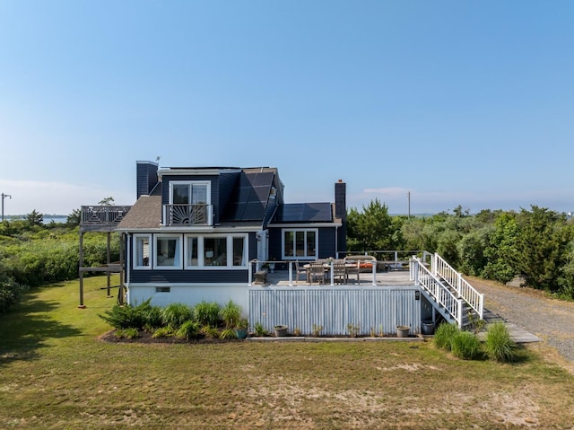 8 The Fairway, Oak Beach, NY 11702 - back of property featuring a chimney, a lawn, roof mounted solar panels, a deck, and a balcony