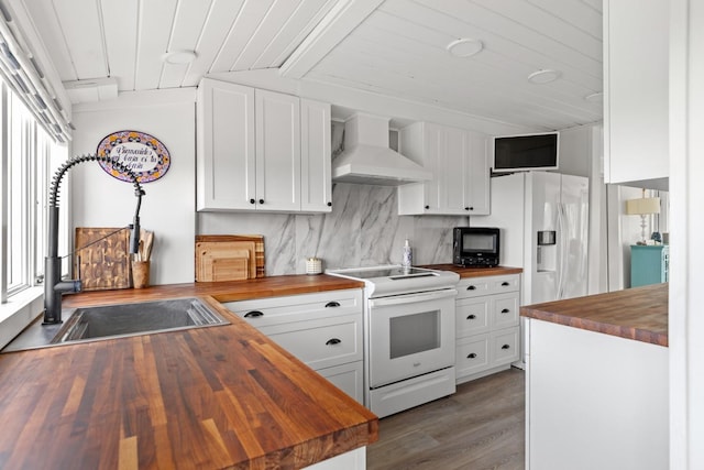 8 The Fairway, Oak Beach, NY 11702 - kitchen with butcher block counters, white appliances, wall chimney exhaust hood, wood finished floors, and white cabinetry