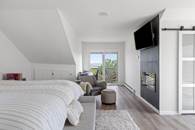 8 The Fairway, Oak Beach, NY 11702 - bedroom with baseboard heating, access to exterior, wood finished floors, a barn door, and a large fireplace