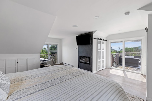 8 The Fairway, Oak Beach, NY 11702 - bedroom with access to exterior, vaulted ceiling, wood finished floors, a premium fireplace, and recessed lighting