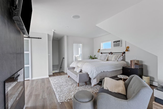 8 The Fairway, Oak Beach, NY 11702 - bedroom featuring wood finished floors, a barn door, an AC wall unit, and baseboard heating