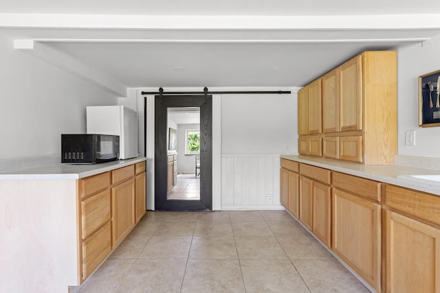 8 The Fairway, Oak Beach, NY 11702 - kitchen with black microwave, a barn door, light tile patterned flooring, light countertops, and light brown cabinetry