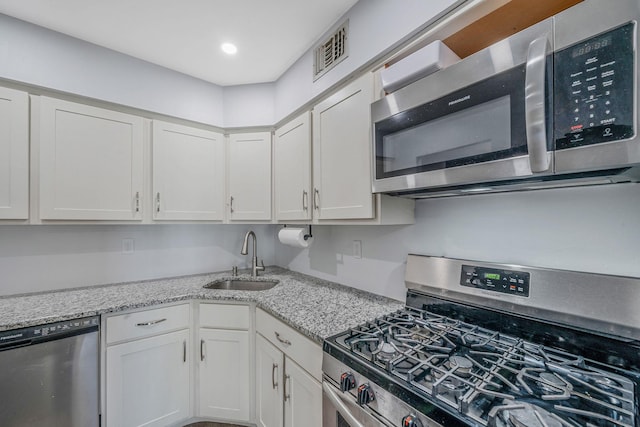 77 Fairview Cir Unit 77, Middle Island, NY 11953 - kitchen featuring appliances with stainless steel finishes, white cabinetry, light stone counters, and recessed lighting