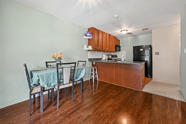 276 Fairview Cir, Middle Island, NY 11953 - kitchen with black appliances, a peninsula, brown cabinetry, dark countertops, and wood finished floors