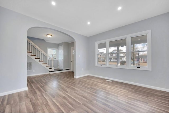 178 N Ocean Ave, Patchogue, NY 11772 - unfurnished living room featuring arched walkways, wood finished floors, stairway, and recessed lighting