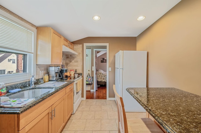 557 Newbridge Rd, East Meadow, NY 11554 - kitchen featuring white appliances, under cabinet range hood, lofted ceiling, dark stone countertops, and backsplash