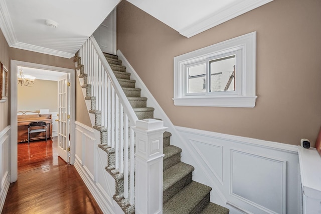 557 Newbridge Rd, East Meadow, NY 11554 - stairs featuring a decorative wall, ornamental molding, wood finished floors, wainscoting, and a chandelier