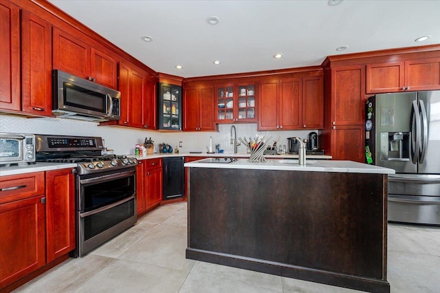 137 Jefferson St, Inwood, NY 11096 - kitchen with stainless steel appliances, reddish brown cabinets, light countertops, tasteful backsplash, and recessed lighting